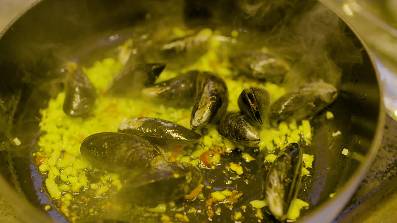 el cocinero cocina mejillones en la sartén