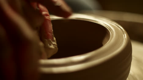 close-up view of hands shaping clay on a pottery wheel