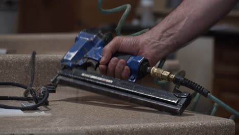 Slow-motion-shot-of-a-tradesman-picking-up-an-air-powered-staple-gun-in-a-workshop