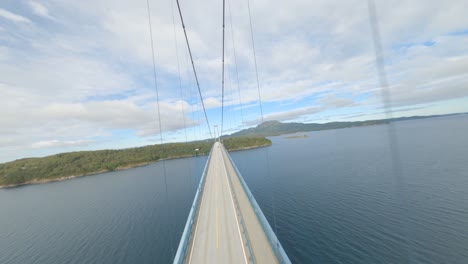 aerial flight over bomla bridge with crossing cars during cloudy day in norway