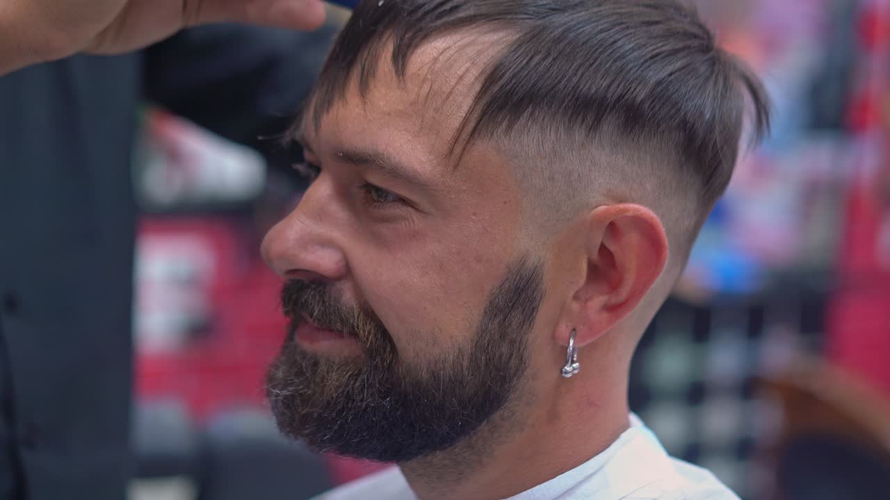 barbero corta el cabello de un hombre con tijeras en una barbería