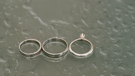Boda-Rings-Newlyweds-And-Engagement-Ring-On-A-Glass-Surface-With-Water-Drops