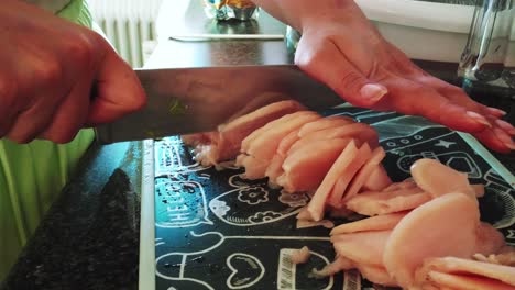 cerrar mujer casa cocina empuja cuchillo a través de pollo congelado con cortes de fuerza