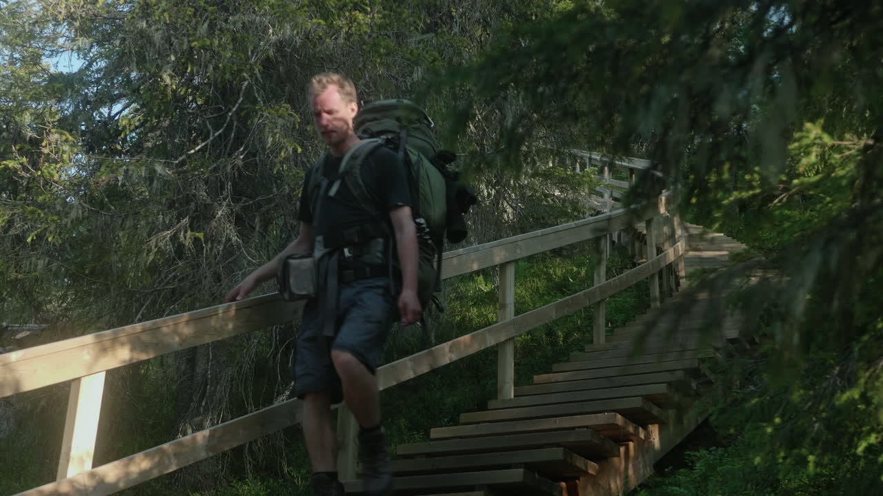 un excursionista descendiendo una escalera en el sendero de karhunkierros en una hermosa atmósfera de puesta de sol, finlandia, ruka