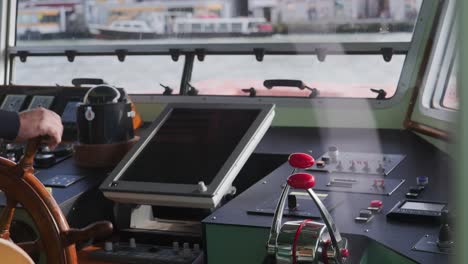 ferry pilot, seen through glass, steers venetian water bus to dockside