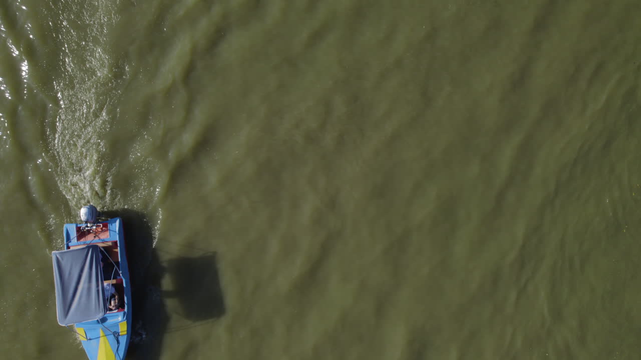 одна небольшая моторная лодка пересекает рамку в озере яркон парк , парк находится в центре тель-авива, посетители приходят на пикник, арендовать лодку и игровые площадки для детей