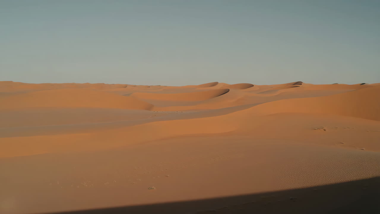 Vast expanse of sandy desert dunes under a clear sky