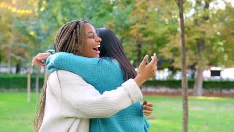 two happy multi-ethnic friends embracing and laughing in a park
