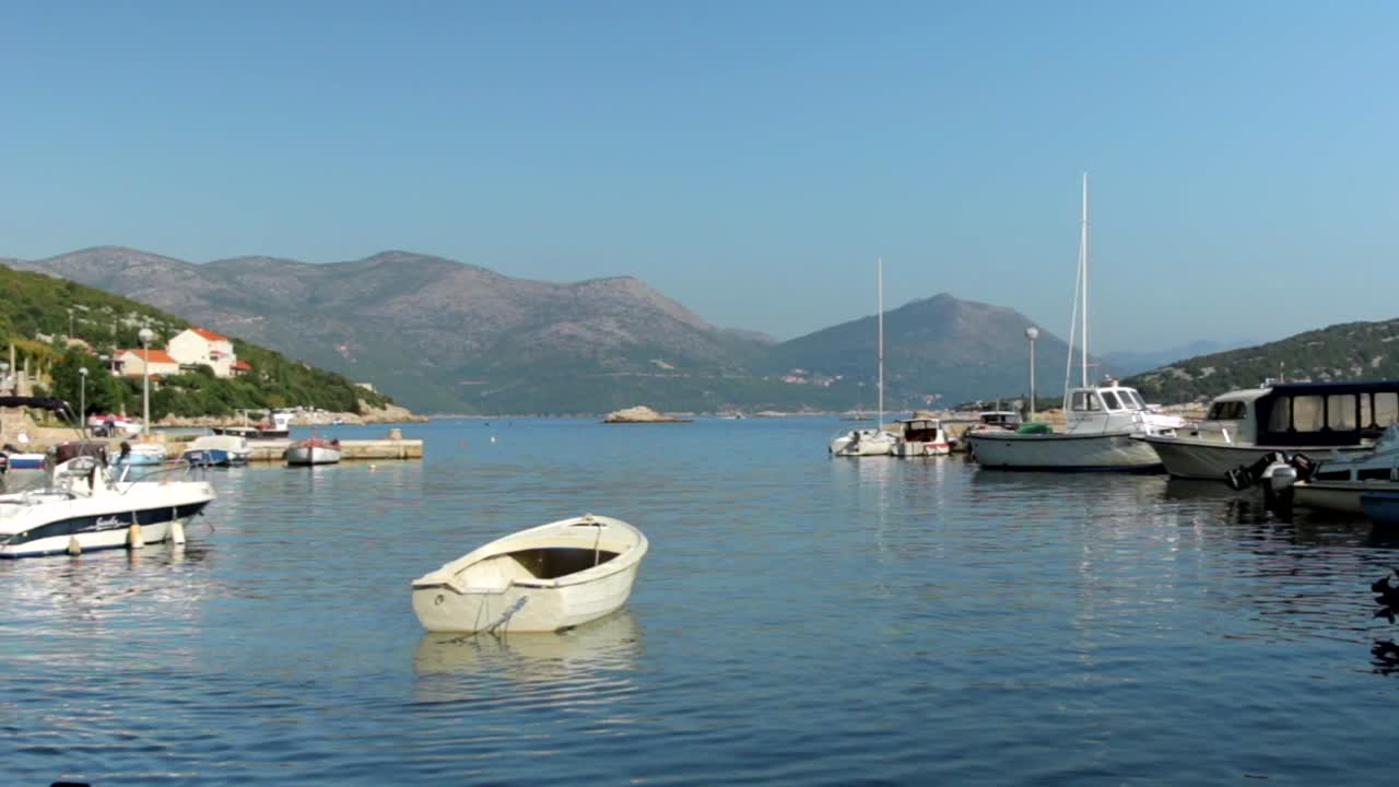 Veduta serena di piccole imbarcazioni in una cala in una giornata limpida e soleggiata con colline in lontananza.