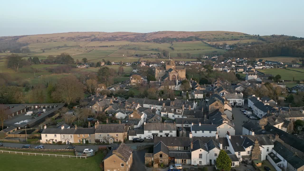 clip en cámara lenta del pueblo medieval de cartmel en cumbria que muestra el histórico priorato de cartmel al atardecer en un día de invierno