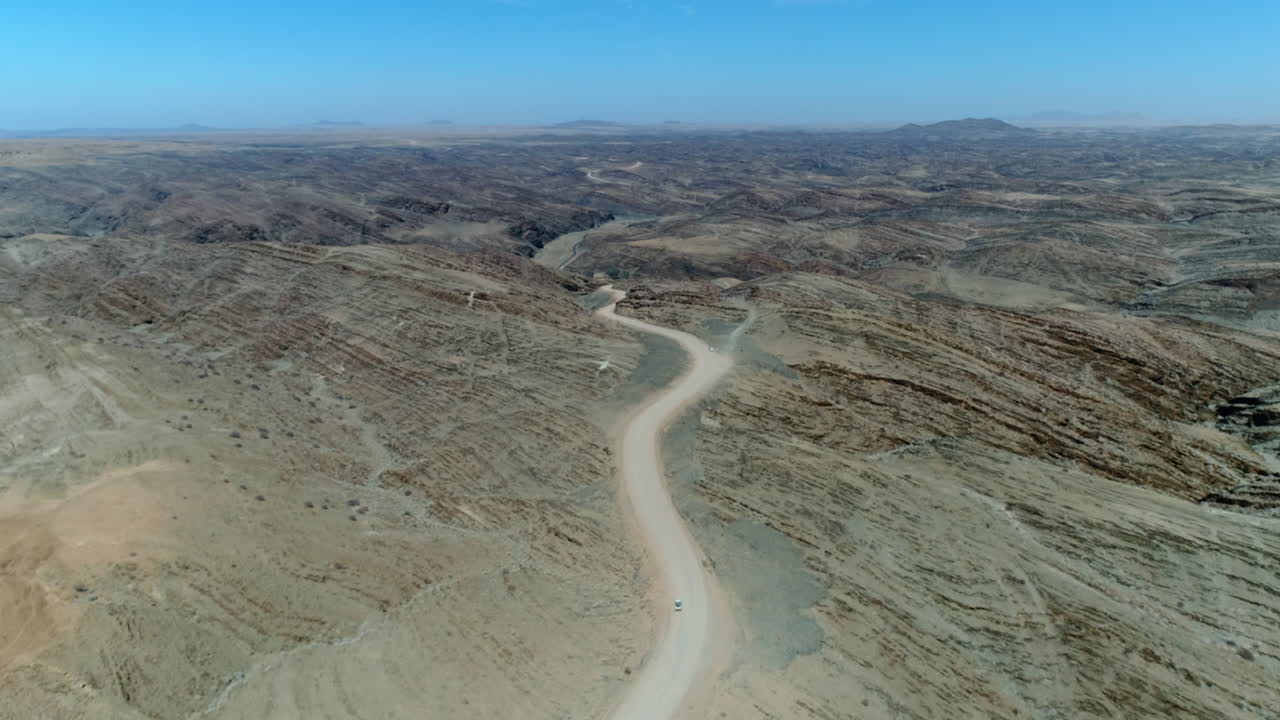 Aerial folowwing a 4WD Jeep on a gravel road between beautiful landscape in Nambia.
