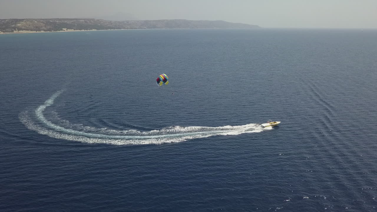 los turistas disfrutan de un colorido paseo en parapente detrás de un barco turístico en aguas azules