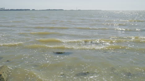 Rising-shot-from-rocky-shore-to-rolling-waves,-Harwich-harbor-visible