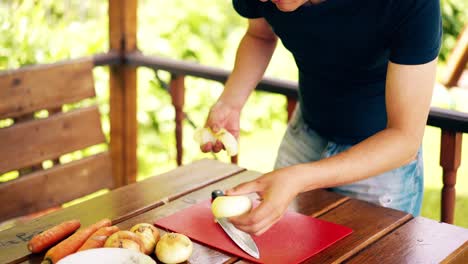 hombre viajando en primer plano está de pie en la casa de verano cocinando pilaf para picnic
