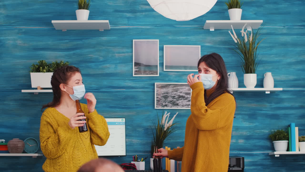 Joyfull women with protective mask discussing in living room