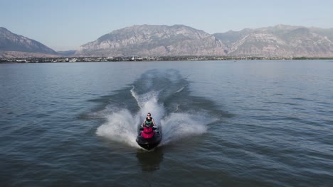 woman riding jet ski waverunner on utah lake surface in summer, aerial tracking