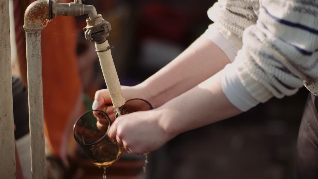 Close-up of glasses being washed under industrial tap