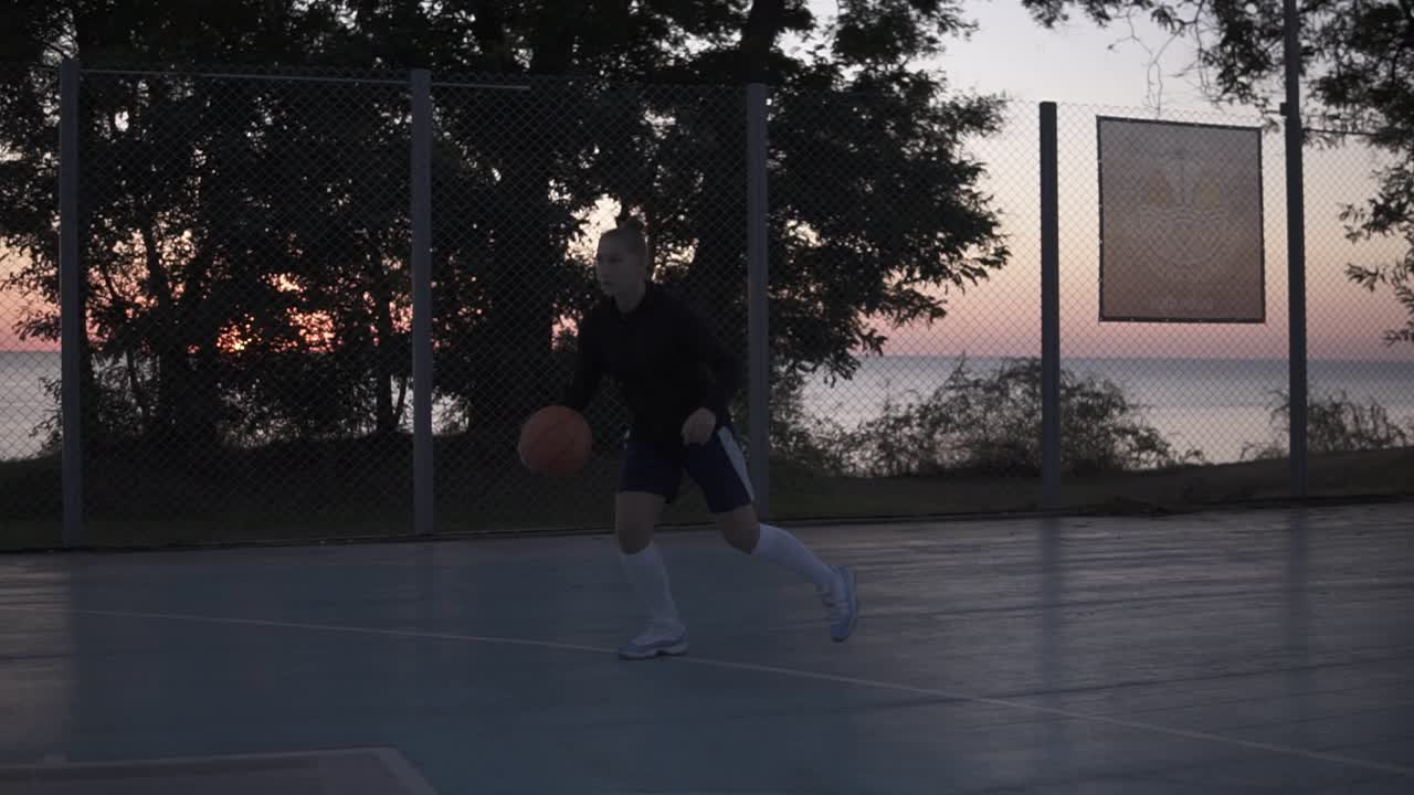 joven jugadora de baloncesto entrenando al aire libre en una cancha de baloncesto