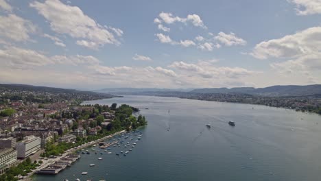 aerial view over lake zürich with passenger ships, a scenic landscape and the swiss alps in the background on a sunny and cloudy spring day.