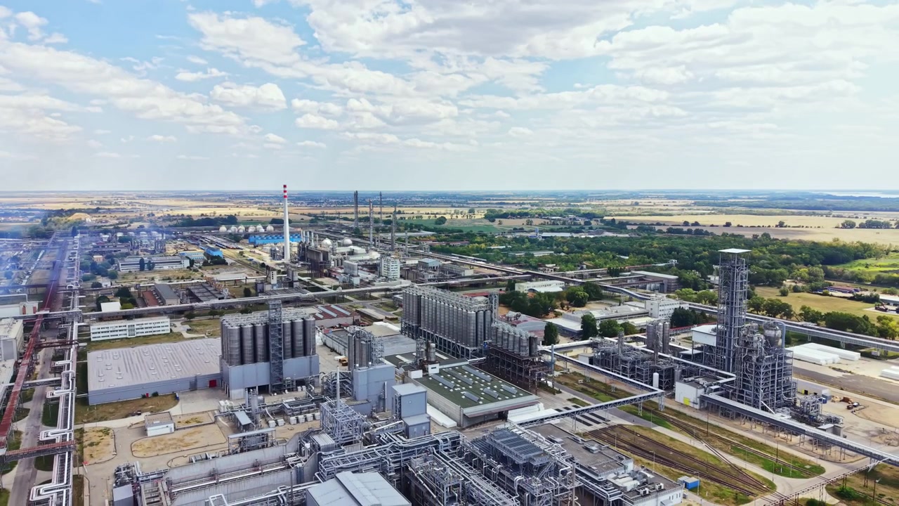 Industrial site shows various structures and machinery under a cloudy sky in a rural area