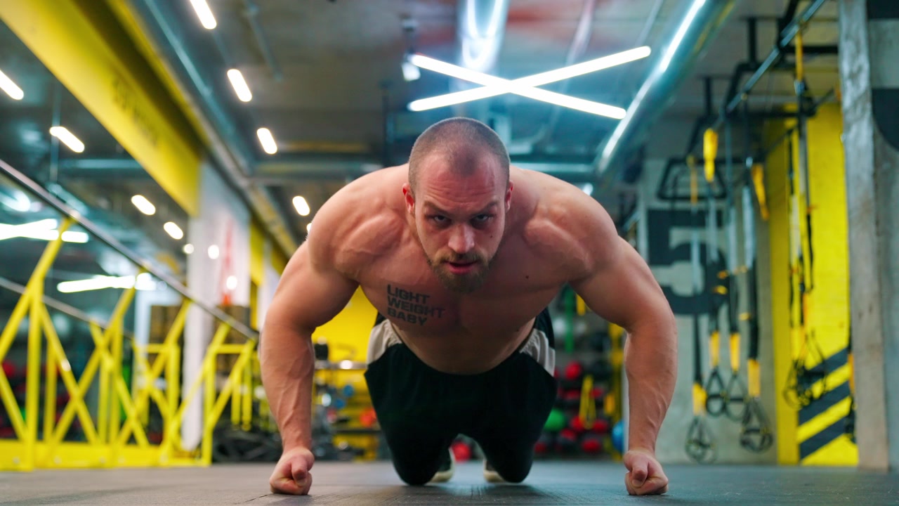 Uomo muscoloso che fa flessioni in una palestra moderna