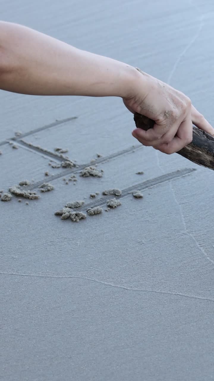 Sequential writing of the word 'Hi' on sand.