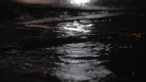 rain puddles and falling drops against car city lights