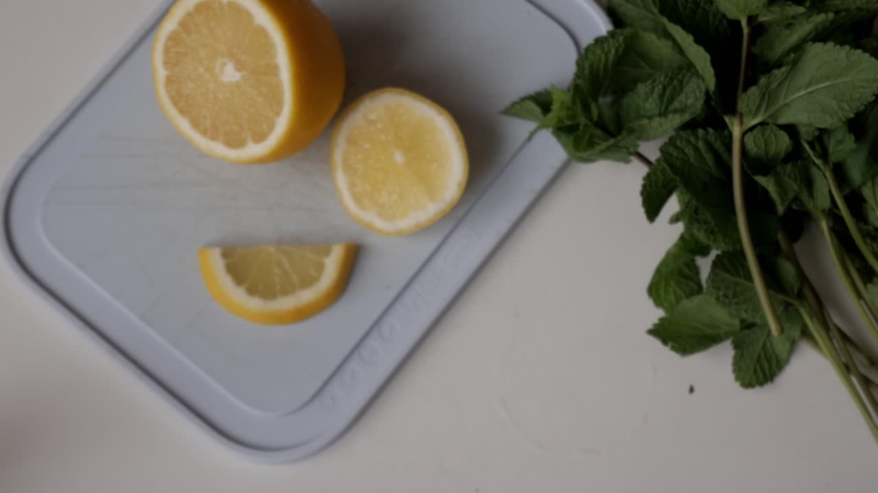 Freshly sliced lemon on a cutting board, with fresh mint leaves beside it, perfect for making lemonade