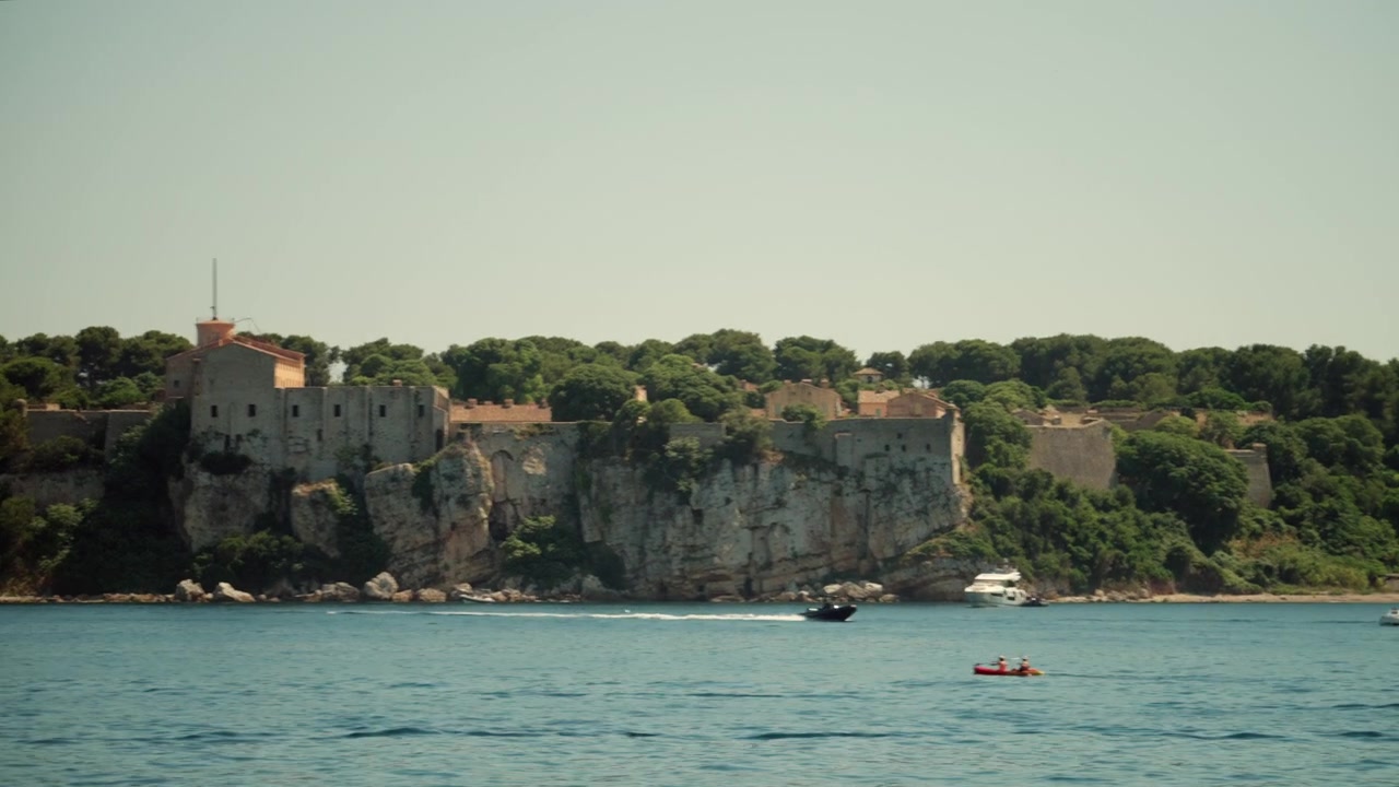 Storica fortezza reale che si erge sulle scogliere dell'isola di Sainte-Marguerite, mare calmo con barche e cielo sereno