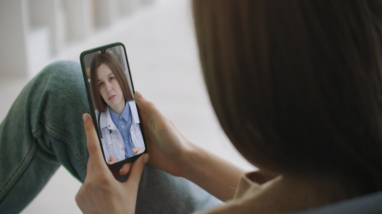 mujer usando la aplicación médica en el teléfono inteligente consultando con el médico a través de videoconferencia. mujer usando el chat en línea para hablar con el terapeuta familiar y chequear posibles síntomas durante la pandemia de coronavirus.