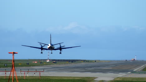 a turboprop propeller airplane touching down on the runway, rear shot