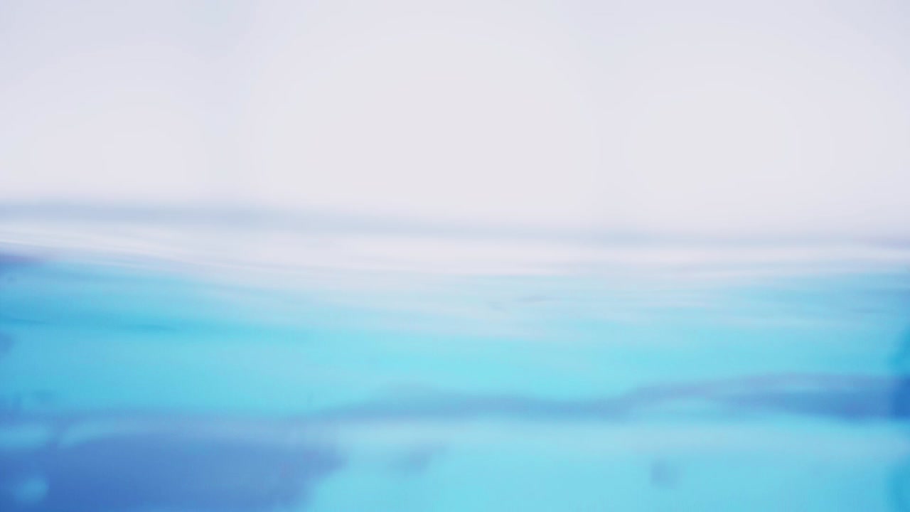 슬로우 모션의 깨끗한 물 표면은 물이 튀는 상점으로 화면을 채우고 기포로 액체 표면을 흔들고 있습니다.