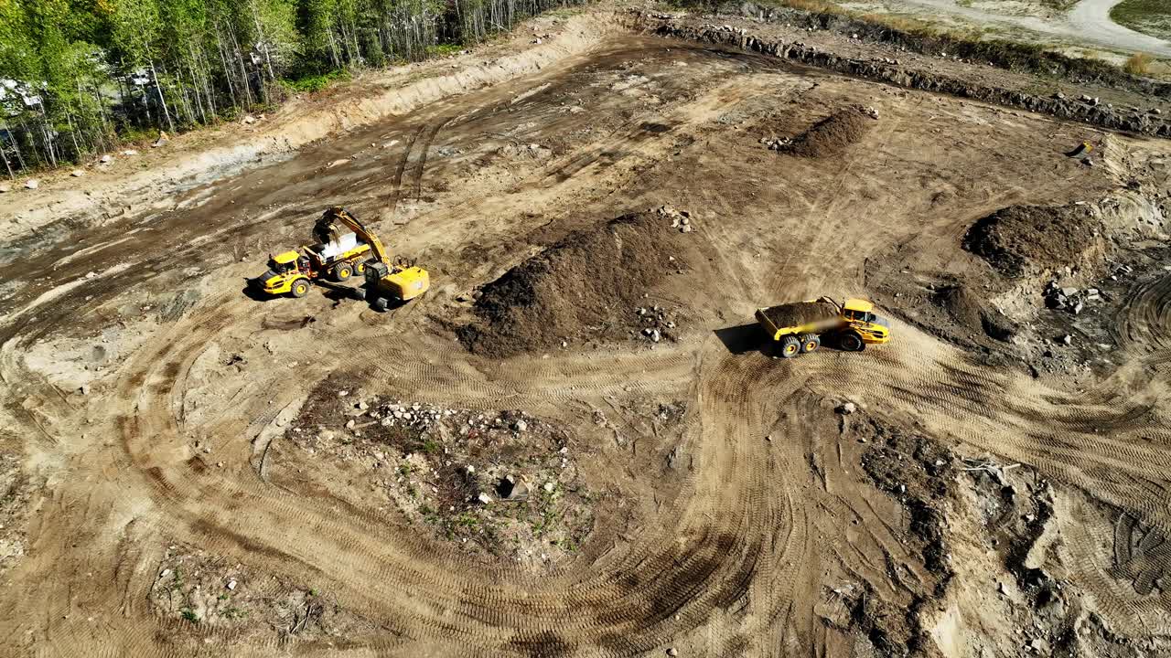 vista aérea de las cargas de la excavadora y del camión de descarga en el sitio de excavación de la construcción