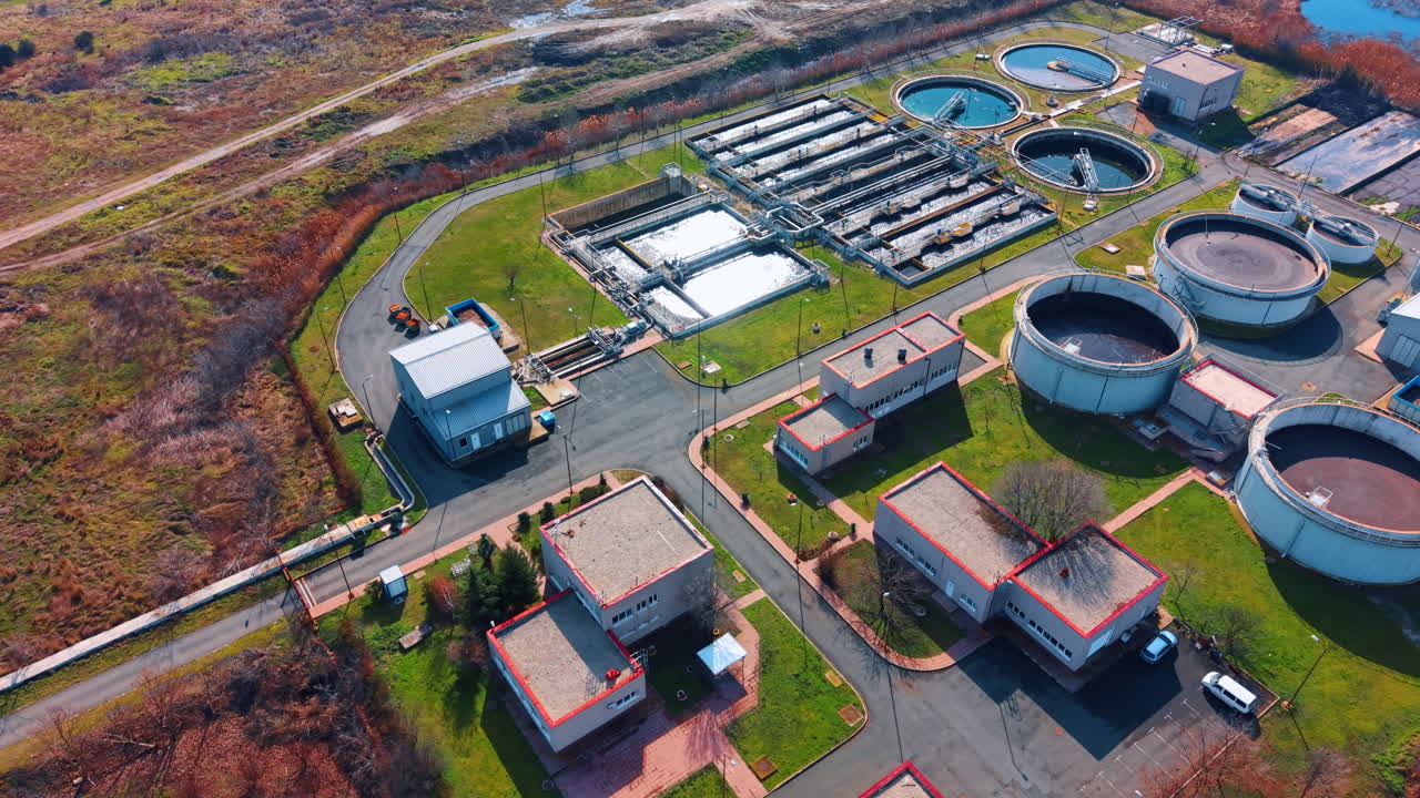 Aerial panorama of water purification station and service buildings. High altitude view of industrial complex with treatment tanks and administrative structures at sunset light