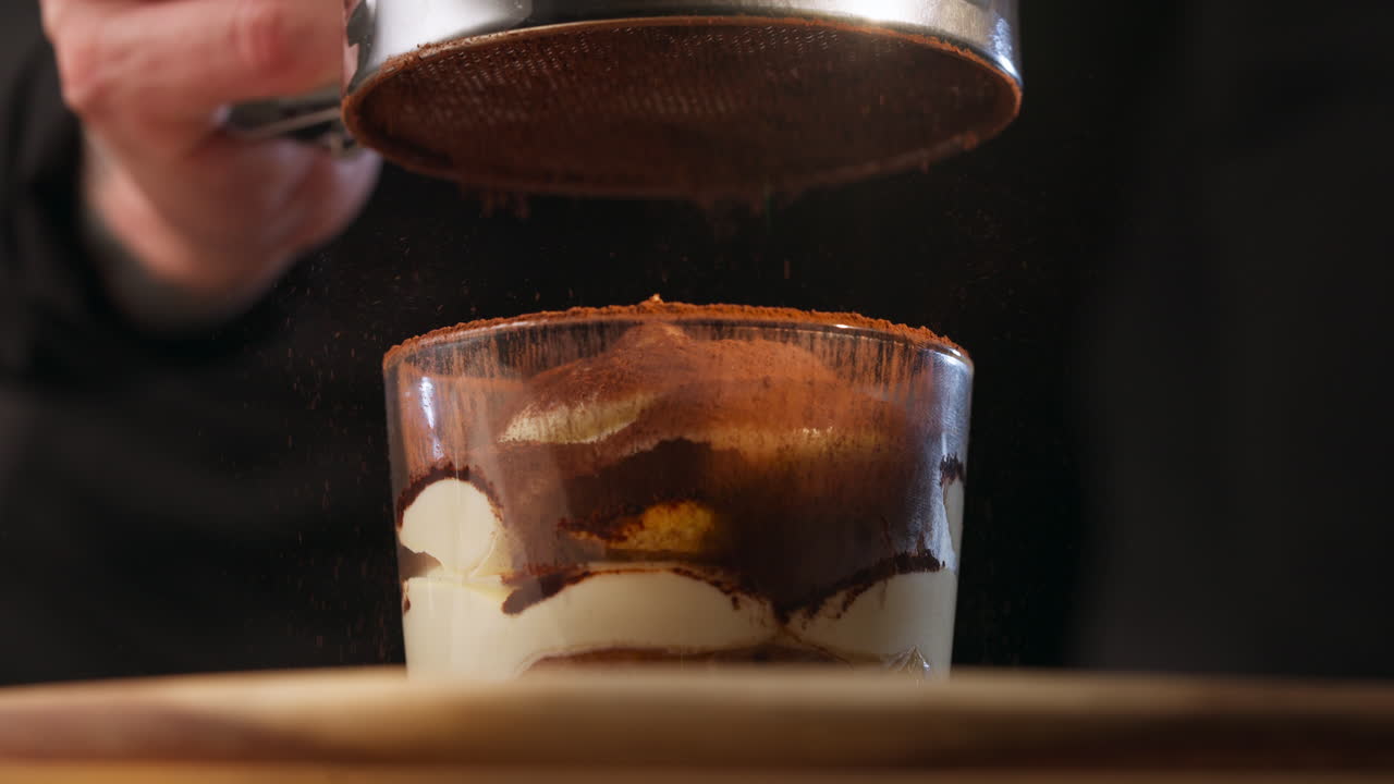 Sifting Cocoa Powder Over Tiramisu Dessert. - closeup shot
