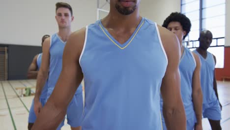 portrait of serious african american male basketball player and diverse team on court, slow motion