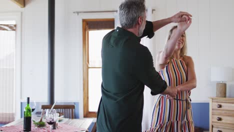 Happy-caucasian-mature-couple-dancing-in-the-sunny-living-room