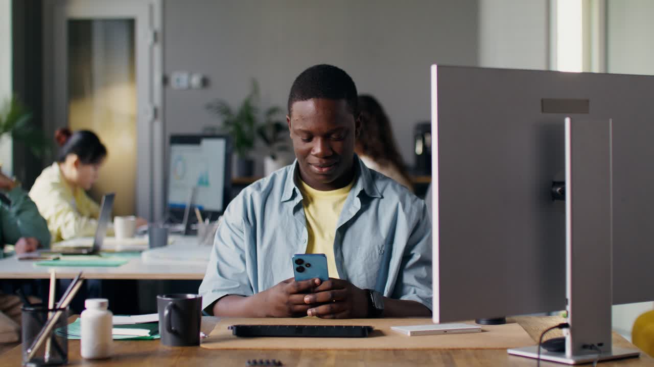 Man looking at smartphone in a busy office