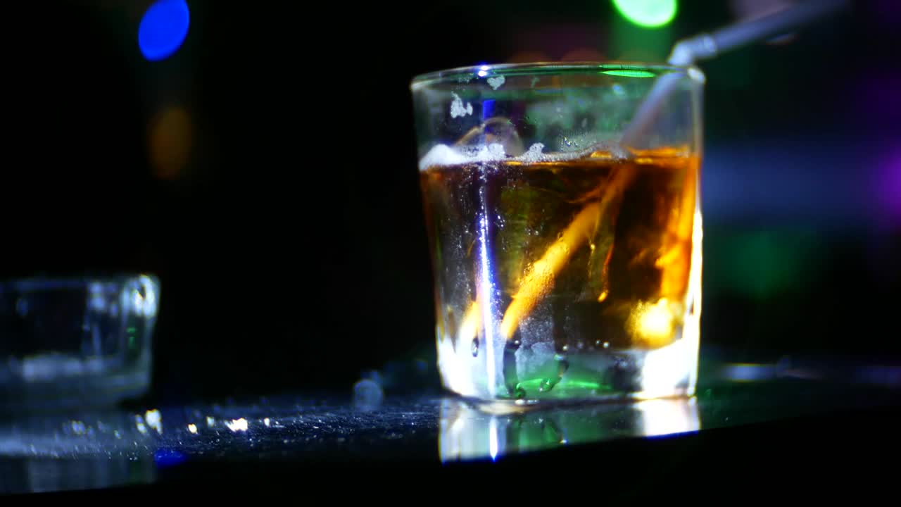 Primo piano di un cocktail alcolico in un bicchiere sul bancone del bar, in discoteca. Sfondo sfocato, 4k.