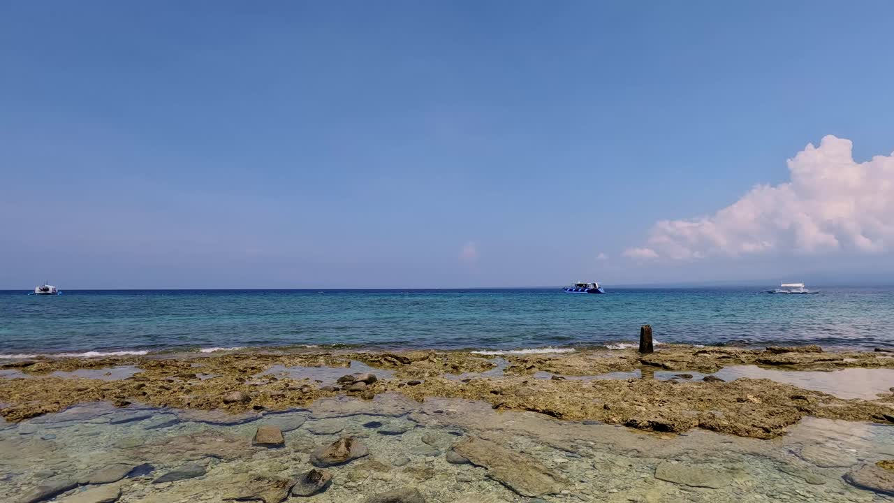 Pan right to the vast expanse of idyllic coastline during the low tide in Apo Island, a popular summer travel destination in Dauin, Philippines