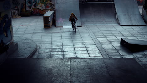 un adolescente jinete de bmx realizando un peligroso salto en la rampa en el parque de skate.