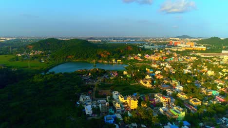 Drone-shot-of-a-city-s-birds-eye-view-with-mountain,-lake-and-houses