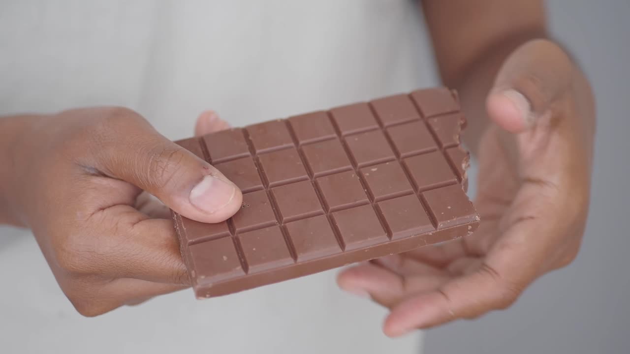 Hands breaking a bar of milk chocolate