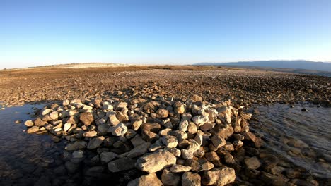 Handheld-camera-walking-over-stony-path-over-water-crossing-made-of-piled-up-stones