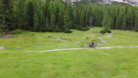 static drone shot of bikepacking cyclist on fanes-sennes-braies park, dolomites