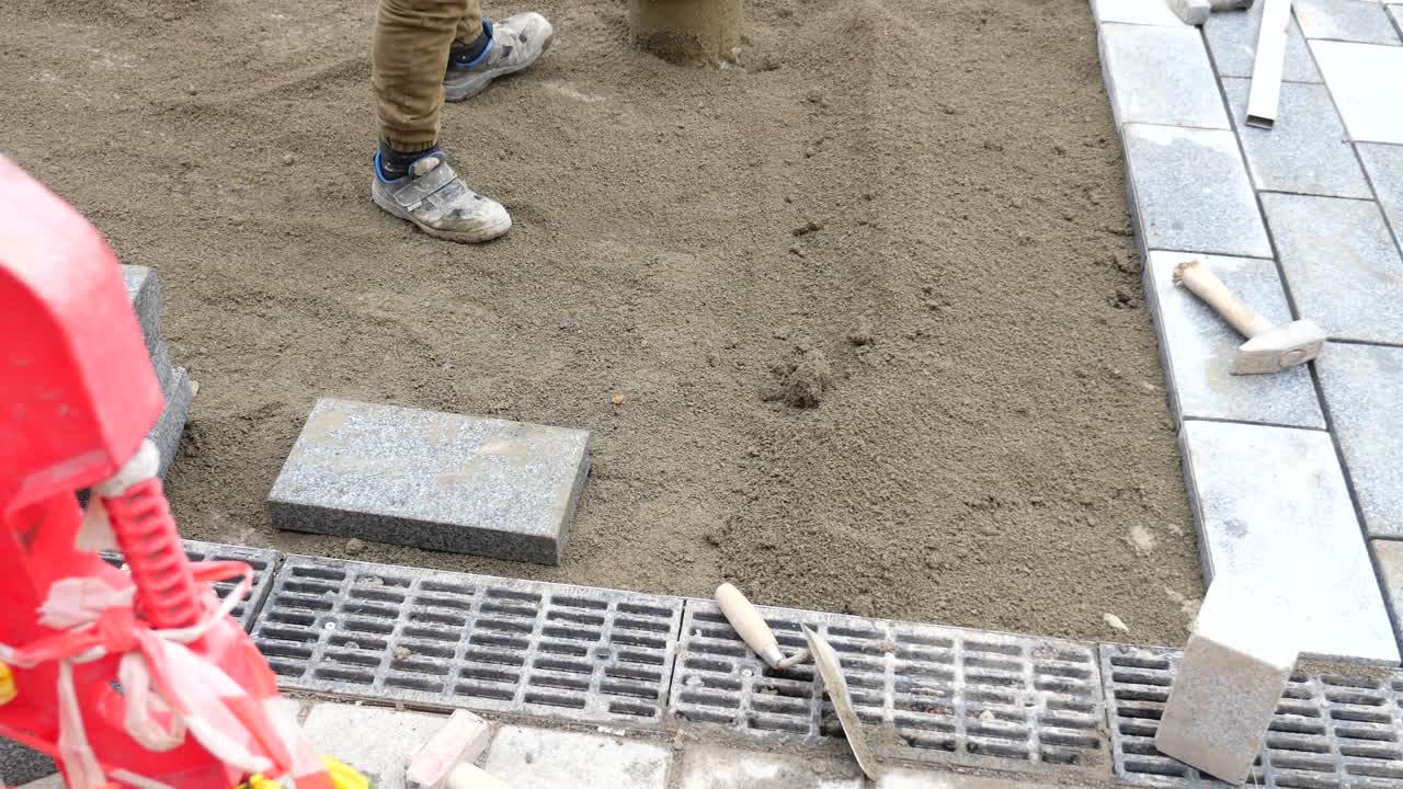 trabajador de la construcción que coloca piedras de pavimentación