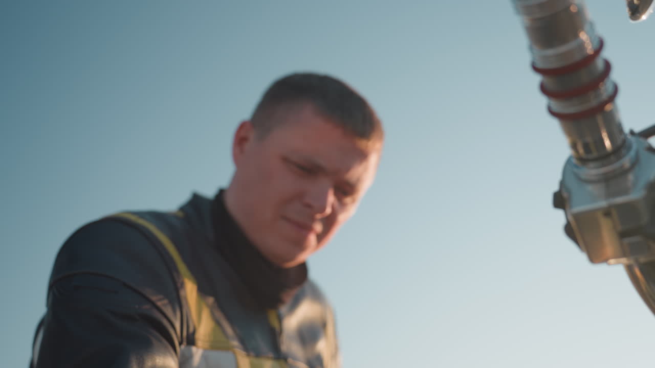 Motorcyklist i læderjakke pudser motorcyklens speedometer og kromtank med en gul klud, mens sollyset skaber en varm refleksion og hjelmen ligger på jorden.