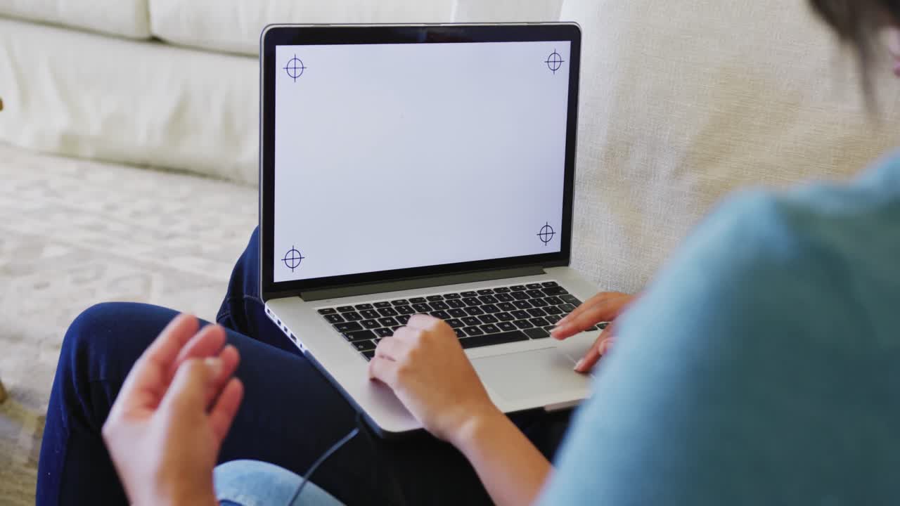 hermanas biraciales sentadas en el sofá y usando una computadora portátil con espacio de copia, en cámara lenta