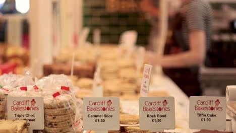 person arranging baked goods at cardiff market