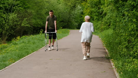 young man assisting elderly woman on walking path